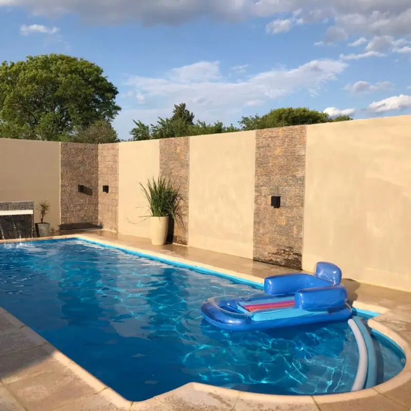 Piscina de fibra de vidrio con borde curvo y solárium instalada por Los Aromos